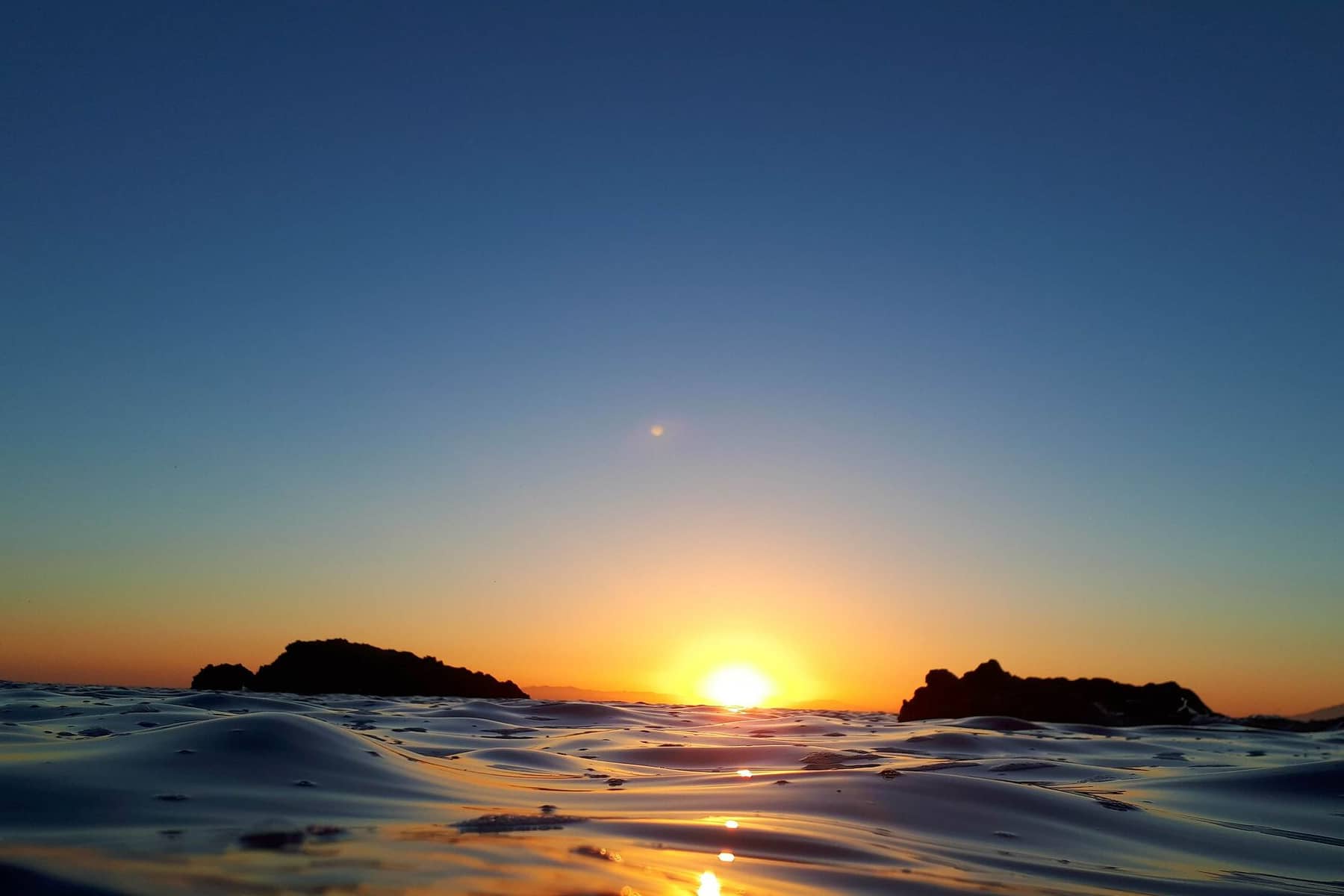 Beautiful sunrise over the ocean, 
                        orange glow reflecting along the horizon